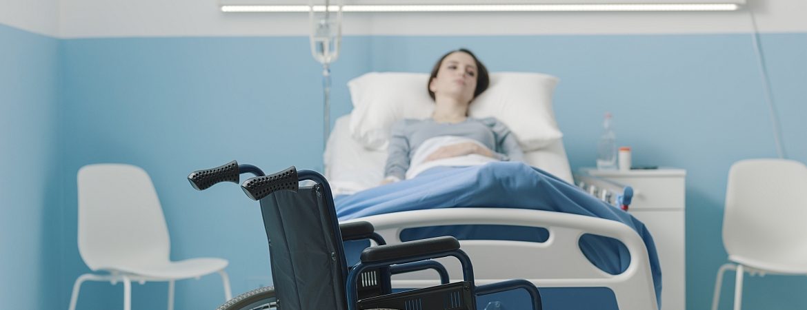 Hospitalized patient lying in bed and wheelchair Hospitalized patient lying in bed and wheelchair in the foreground, medical treatment and injury concept